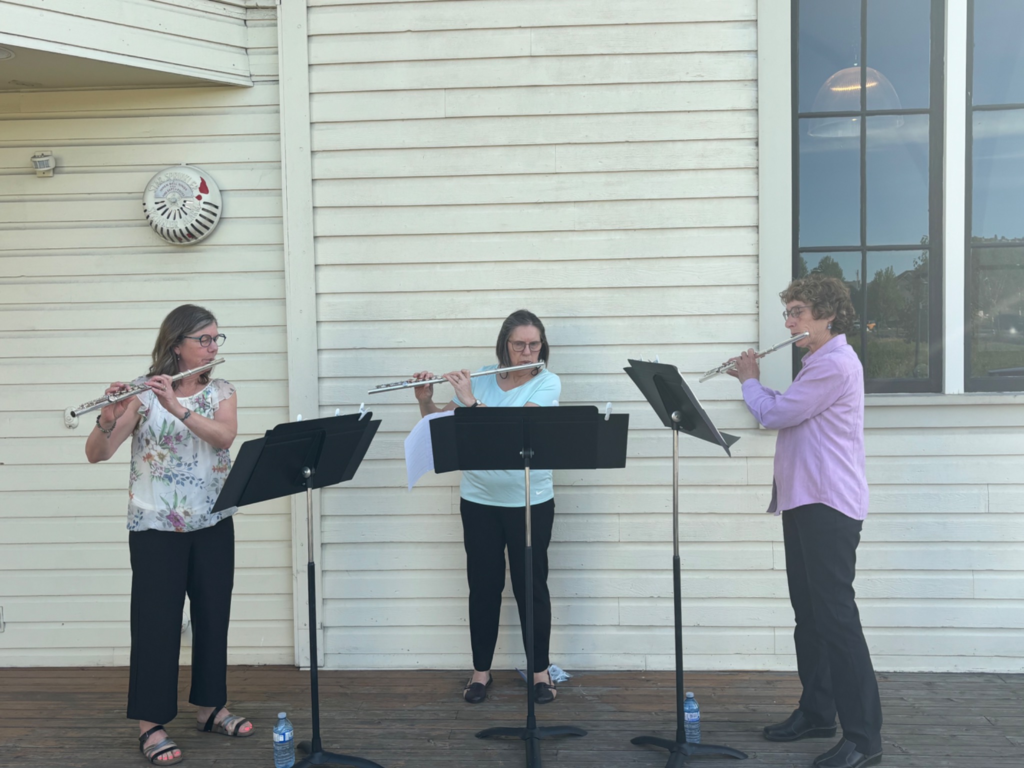 Three flutists performing together outdoors